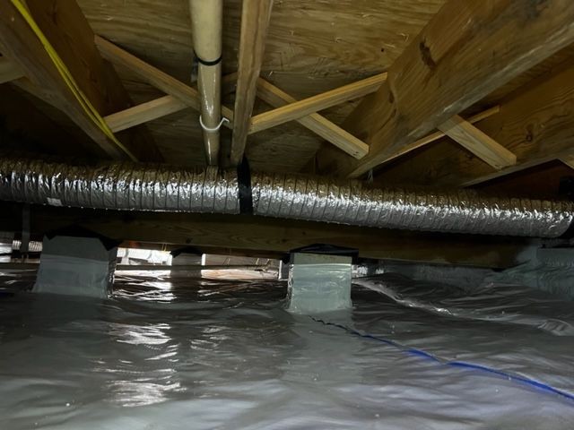 View of a crawl space with exposed wooden beams and an insulated duct running along the ceiling.